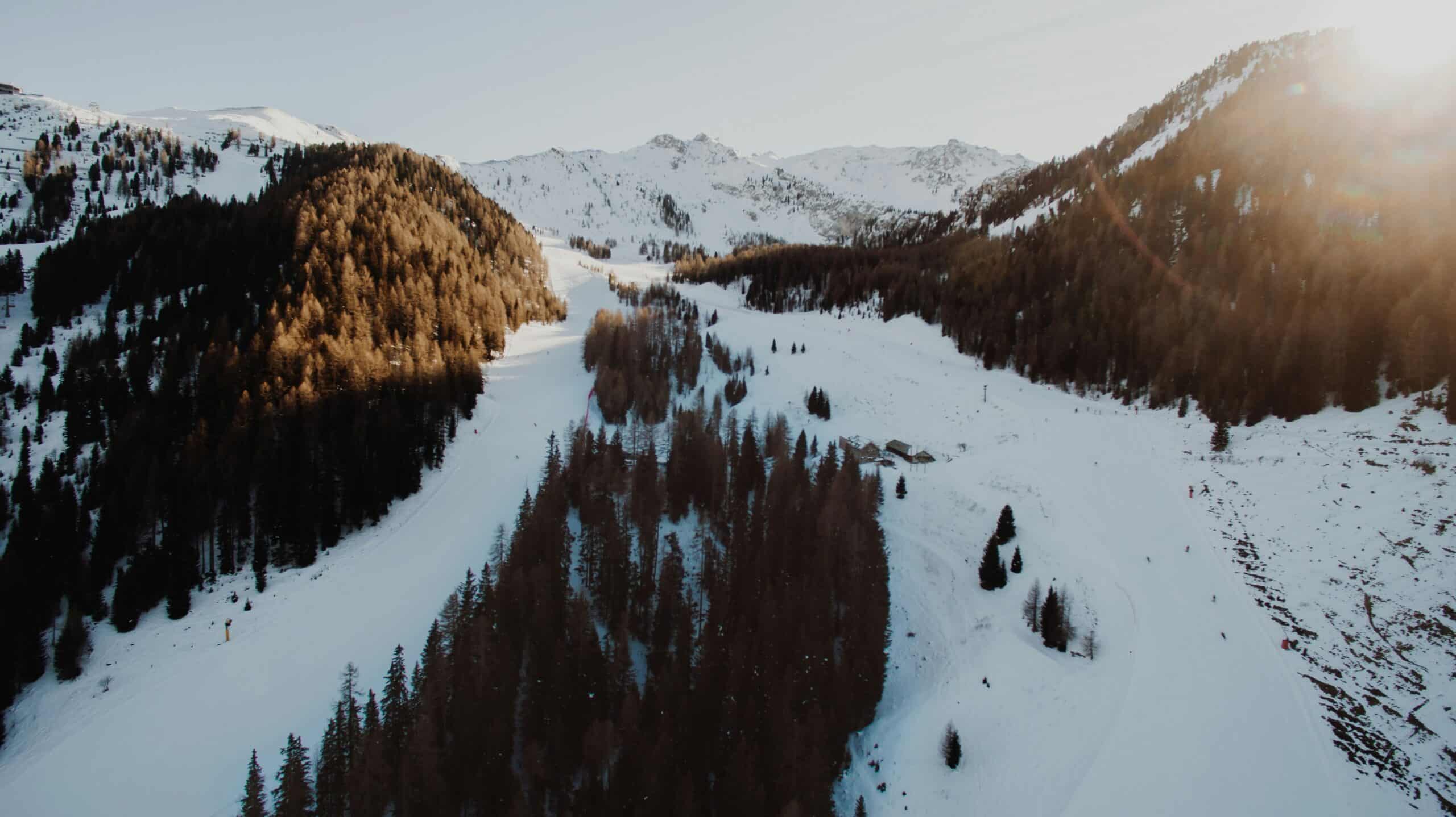 Panorama di piste da sci innevate tra boschi e montagne in Italia